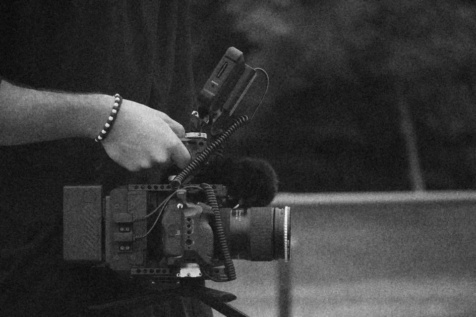 Caméra de cinéma tenue à l'épaule pendant un tournage WATT Production, en noir et blanc