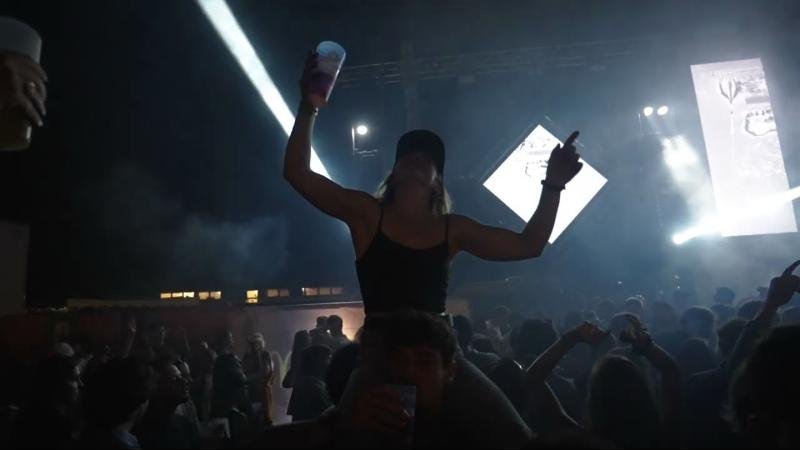 Festivalière perchée sur des épaules, bras levés devant la scène et les lasers du Martine Club
