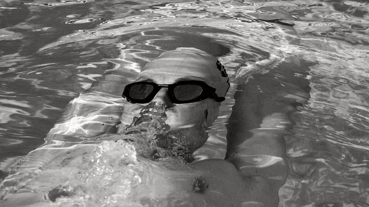 Nageur sur le dos avec des lunettes Enihcam, reflets de lumière dans l’eau, en noir et blanc