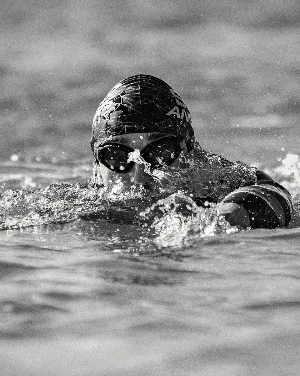 Triathlète nageant en eau libre avec des lunettes Enihcam à verres teintés, en noir et blanc
