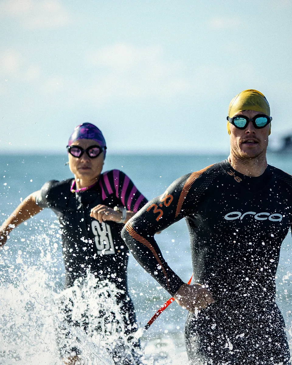 Deux triathlètes en combinaison sortent de la mer en courant