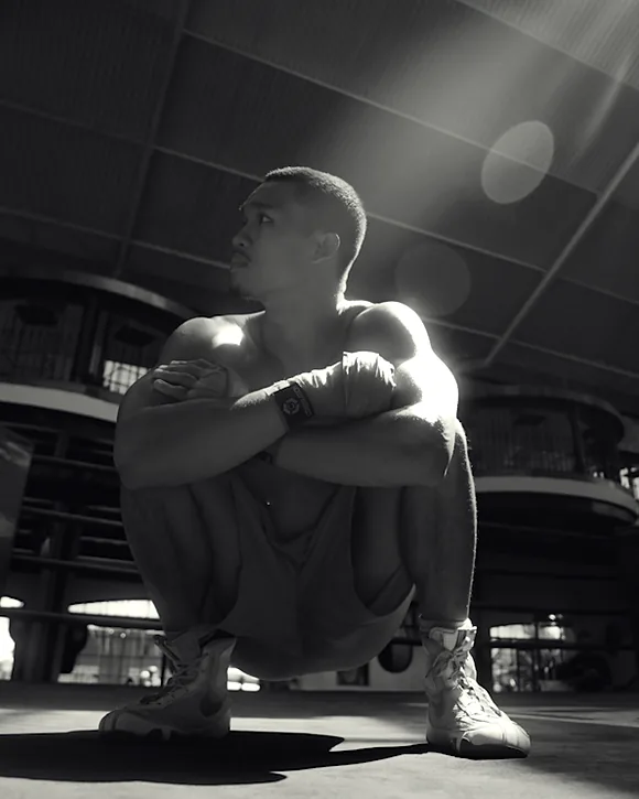 Boxeur accroupi sur le ring en contre-plongée, en noir et blanc