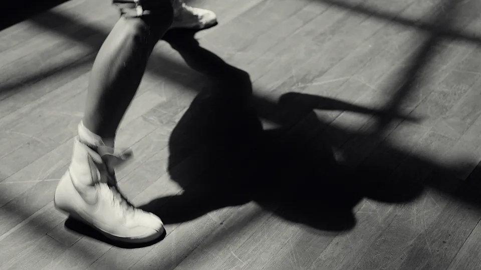 Chaussures de boxe et ombre d’un boxeur sur le parquet, en noir et blanc