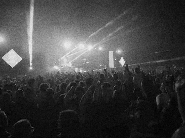 La foule du Martine Club en plan large, bras levés face à la scène et aux faisceaux de lumière, en noir et blanc